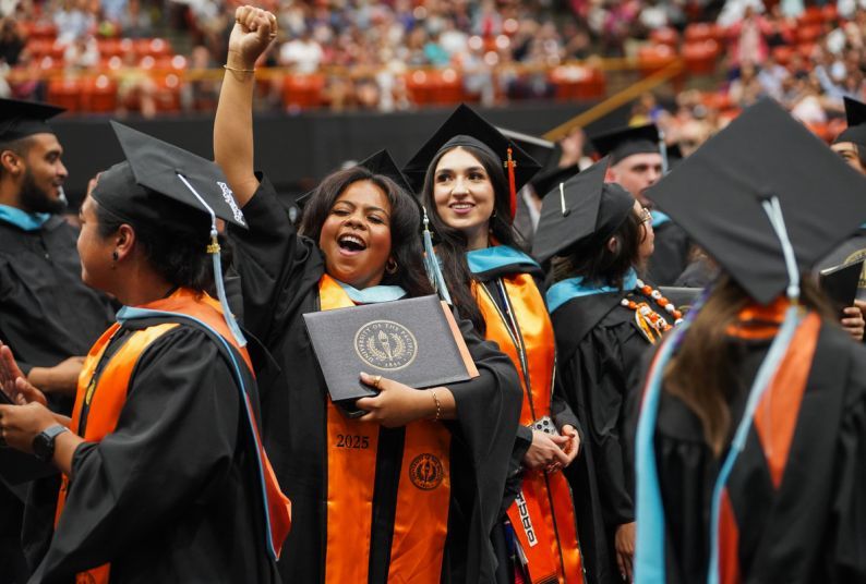 students hold their diplomas at a commencement ceremony